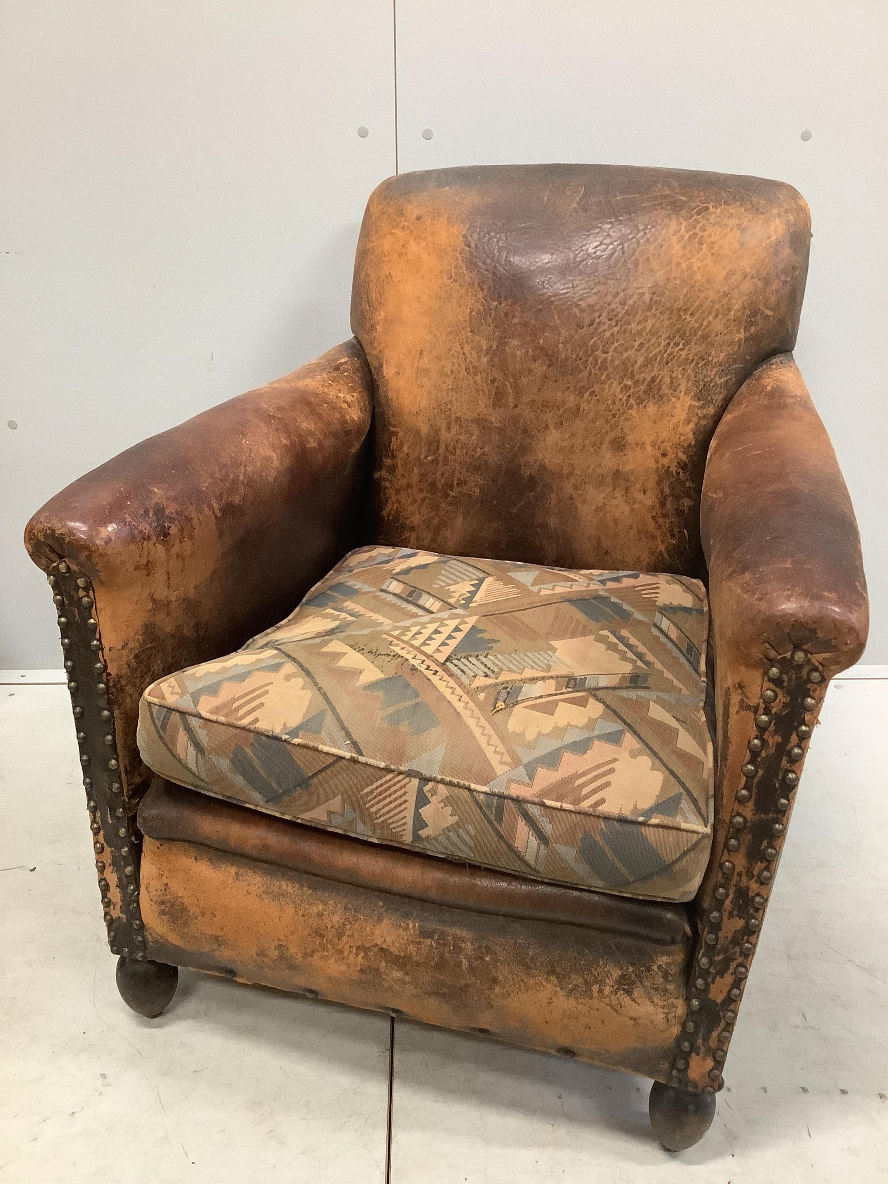 A pair of early 20th century French leather club armchairs, width 73cm, depth 74cm, height 83cm. Condition - poor to fair